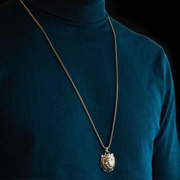 Gold-toned necklace featuring a sculpted lion head pendant on a substantial chain, displayed against neutral background.