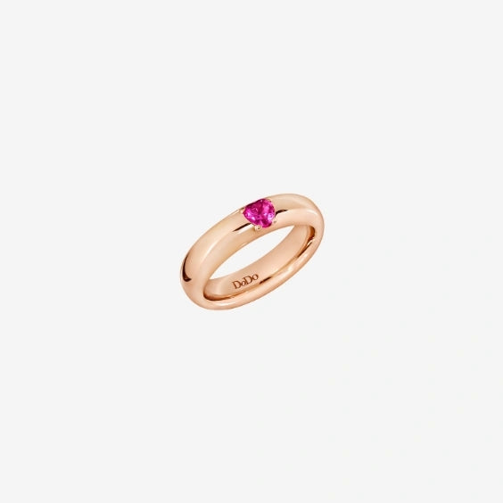 Rose gold ring featuring a pink gemstone center on a polished band, photographed on soft neutral background.