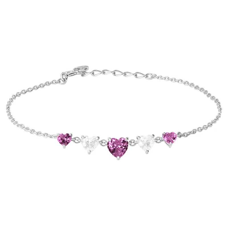 Close-up silver chain bracelet with alternating pink and clear heart-shaped gemstones on wrist